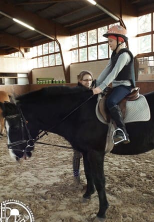 Ein Mädchen reitet einen Rappen in der Reithalle